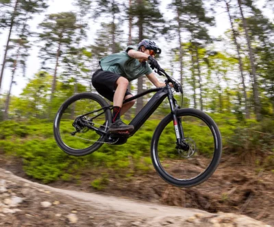 Rider on an a Whyte 505 Ebike jumping on a mountain bike trail