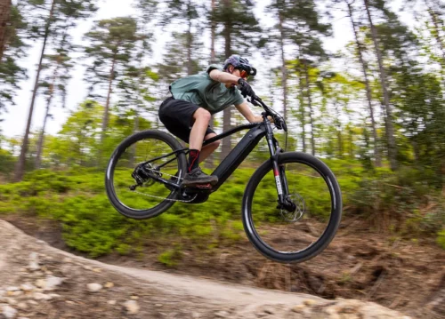 Rider on an a Whyte 505 Ebike jumping on a mountain bike trail